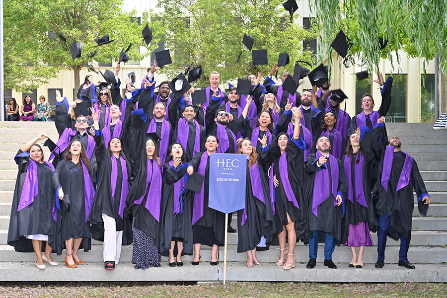 A group of EMBA participants tossing their hat at graduation