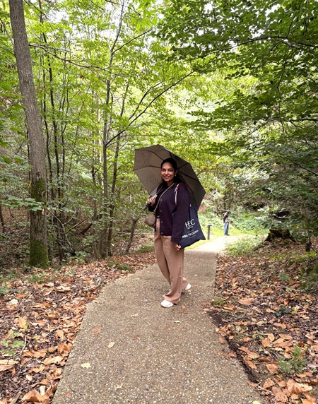 MBA Participant Aayushee Shukla standing in the forest of HEC Paris with an umbrella