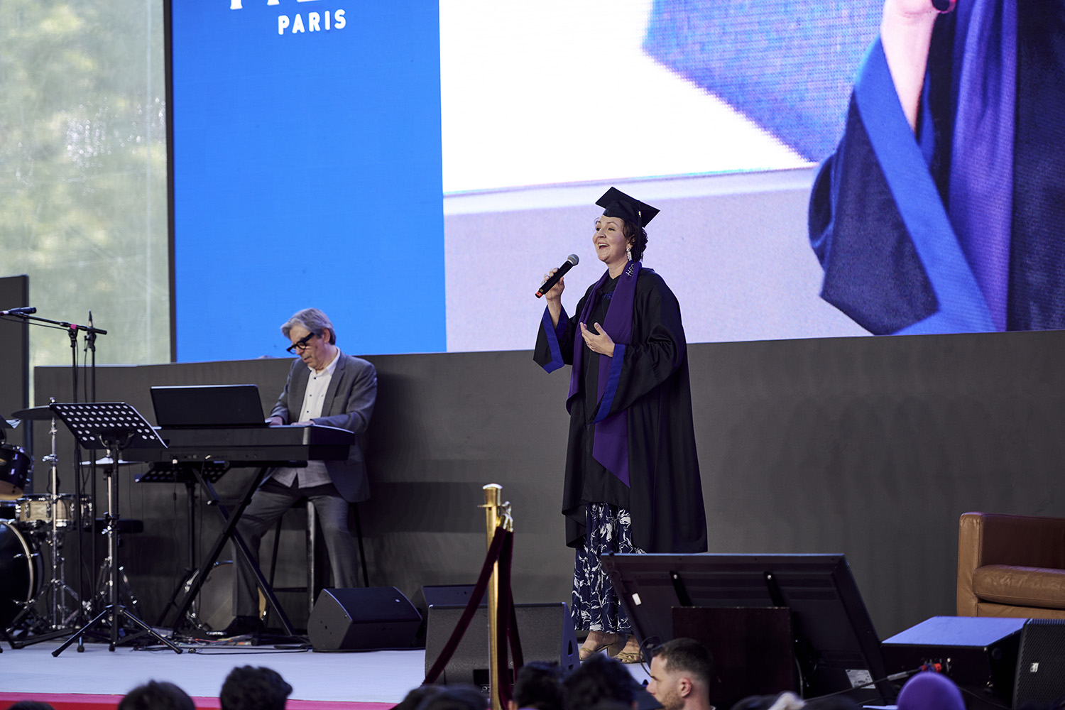 EMBA participant Elizabeth Baker singing onstage at graduation