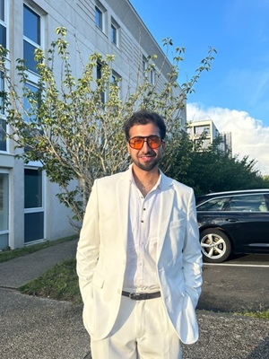 Harivansh Gahlot standing in a white suit on campus