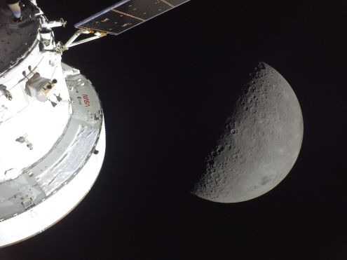 Orion in the Spotlight - art002e009566 (April 6, 2026) - NASA’s Orion spacecraft is seen in the foreground, lit up by the Sun. A first quarter Moon is visible behind it. NASA - art002e009566 (April 6, 2026)