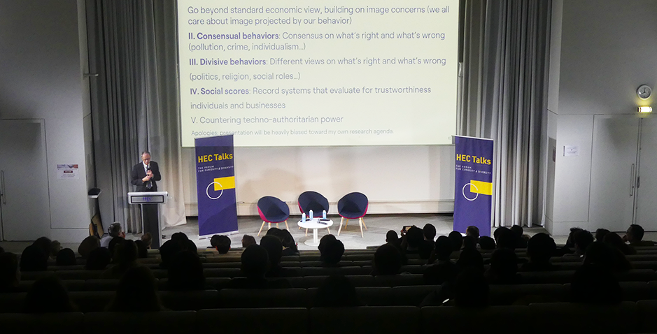 Conference at HEC Paris as part of the HEC Talks series, featuring jean tirole presenting on economic behaviors and social scores to an engaged audience in an auditorium.