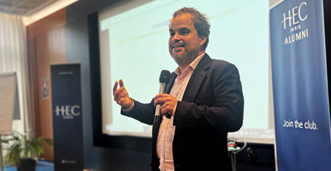 Jeremy Ghez speaking at an HEC Paris Alumni event, microphone in hand.