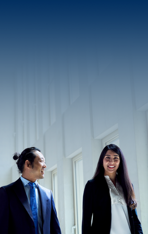 Two students walking in the S building wearing business attire