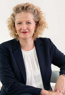 Portrait of the Dean of Executive Education at HEC Paris, seated and facing the camera, wearing a dark blazer and white blouse.
