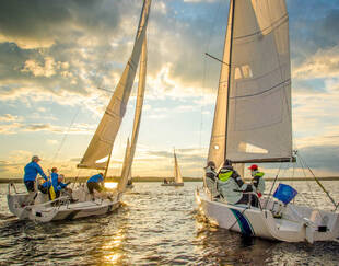 Deux voiliers avancent dans la mer face au coucher du soleil