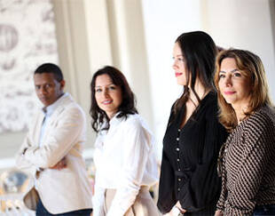 Groupe de quatre personnes posant ensemble dans un environnement lumineux et moderne