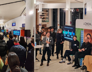 L'Oréal & HEC Paris: Fostering Leadership and Innovation Through Collaboration. Students and company representatives engage in discussions during the Carrefours HEC event at the Hall of Honor. A digital screen displays participating companies, while a partnership board showcases leading firms like L'Oréal, KPMG, and Accenture, highlighting strong corporate-academic collaboration