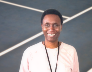 Portrait d'Henriette Leparoux, ancienne athlète et directrice marketing, souriante devant un terrain de sport.