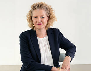 Portrait of the Dean of Executive Education at HEC Paris, seated and facing the camera, wearing a dark blazer and white blouse.