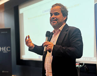 Jeremy Ghez speaking at an HEC Paris Alumni event, microphone in hand.