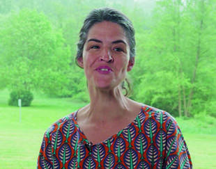 Chloé Renault, en extérieur devant un paysage verdoyant, s'adresse à la caméra