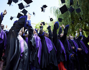 EMBA students throwing up their graduate caps in the air