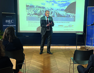  François Gemenne lors d'une masterclass HEC Paris Executive Education, devant une publicité pétrolière des années 1960