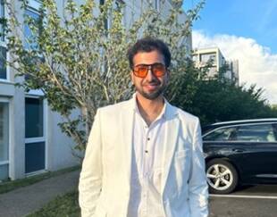 Harivansh Gahlot standing in a white suit on campus