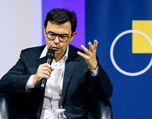 Rodolphe Durand, seated with a microphone, speaks and gestures during a panel discussion