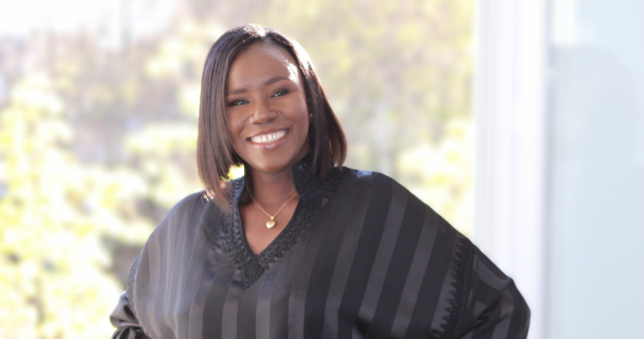 Sokhna Ndiaye souriante, en boubou noir élégant, devant une fenêtre baignée de lumière 
