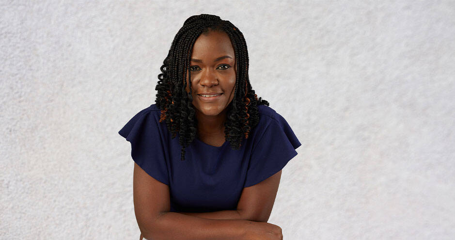 Portrait of Helen Arrey, HEC Paris EMiF 2025 alumna, smiling with arms crossed, wearing a navy blouse, posing in front of a light background.