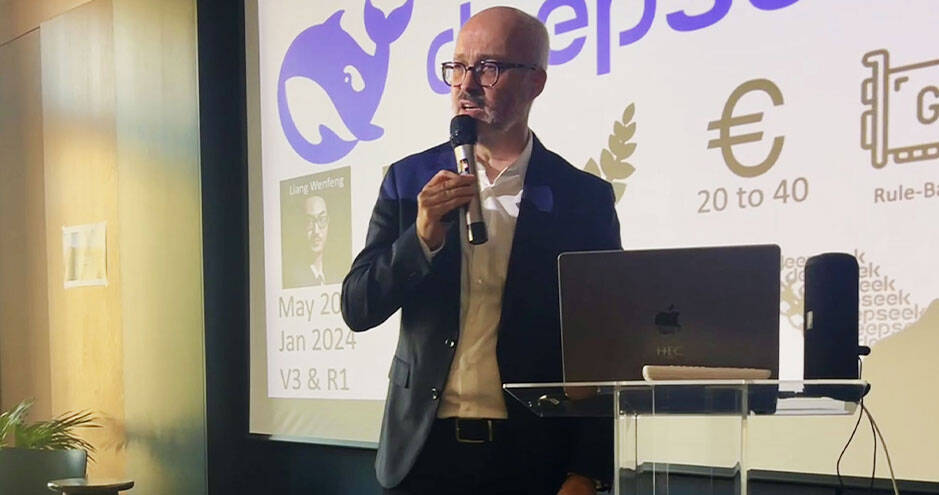 Vincent Fraitot, Associate Professor at HEC Paris, speaking during a masterclass on generative AI, standing at a podium with a microphone and presentation slides projected behind him.
