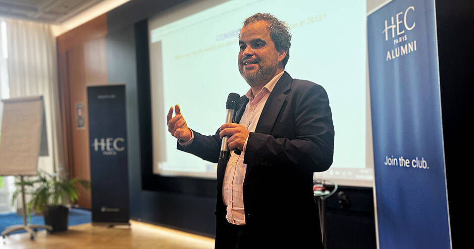 Jeremy Ghez speaking at an HEC Paris Alumni event, microphone in hand.