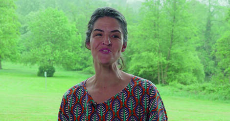 Chloé Renault, en extérieur devant un paysage verdoyant, s'adresse à la caméra