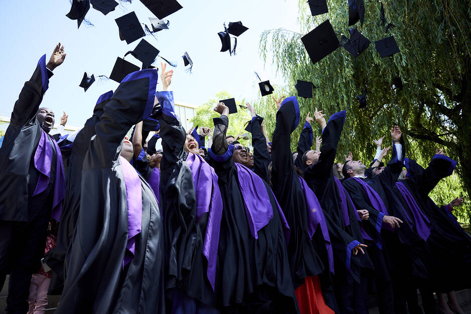 EMBA students throwing up their graduate caps in the air