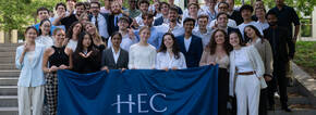 group of summer school students holign HEC flag outside